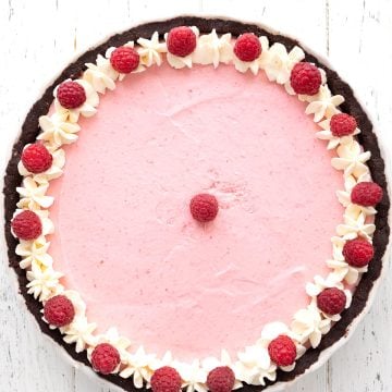 Top down image of keto raspberry tart on a white wooden table.