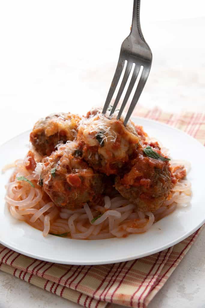 A fork digging into a plate of keto meatball casserole.