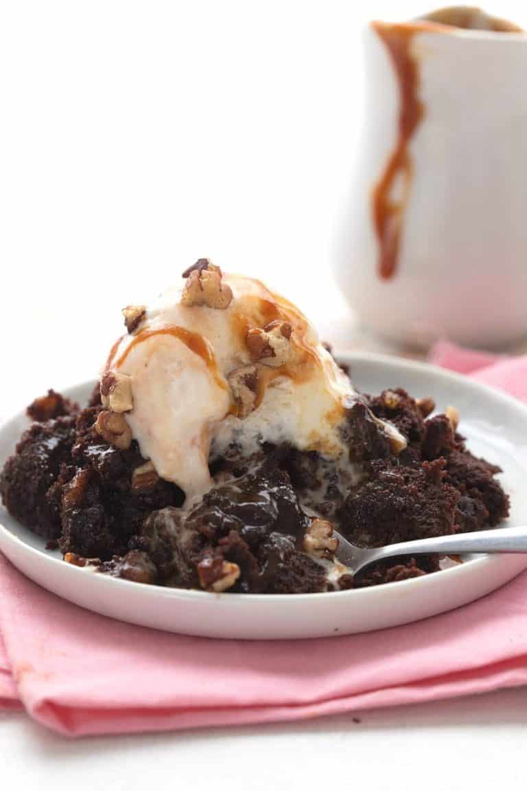 Gooey keto slow cooker brownies on a white plate over a pink napkin.