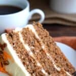 Titled image of The Best Keto Carrot Cake with a slice of cake on a white plate and a cup of coffee in the background.