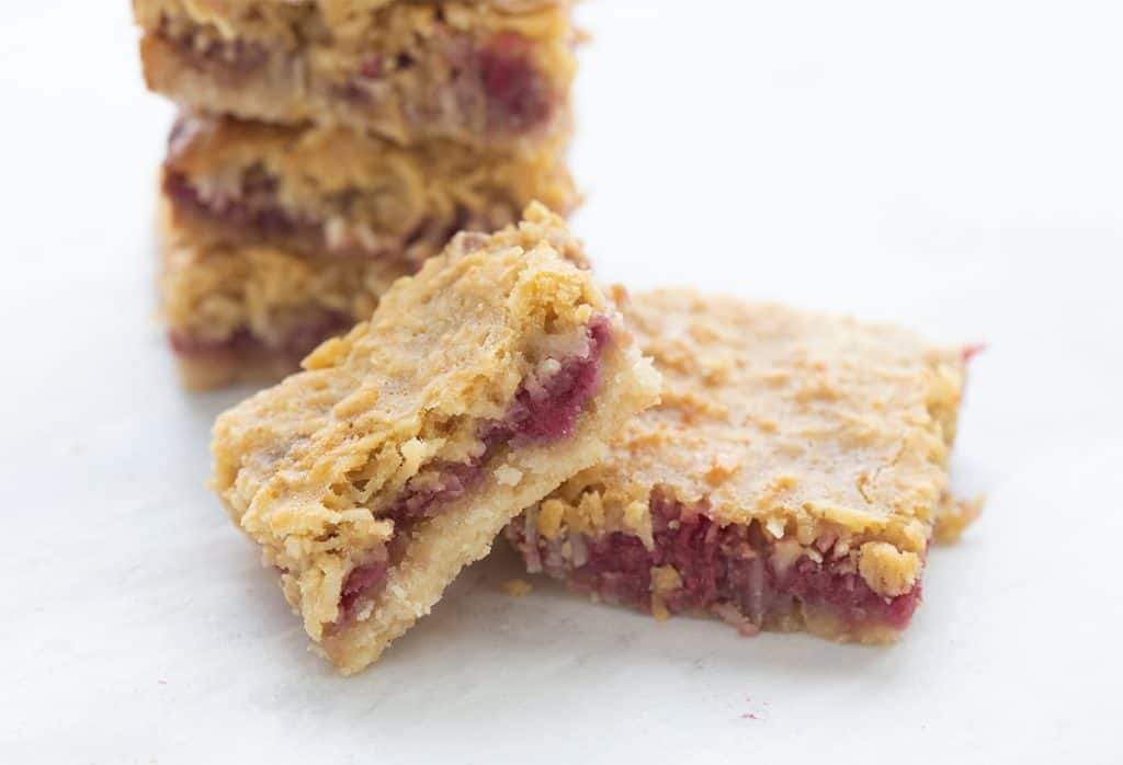 Close up shot of keto raspberry coconut bars with a bite taken out of one.