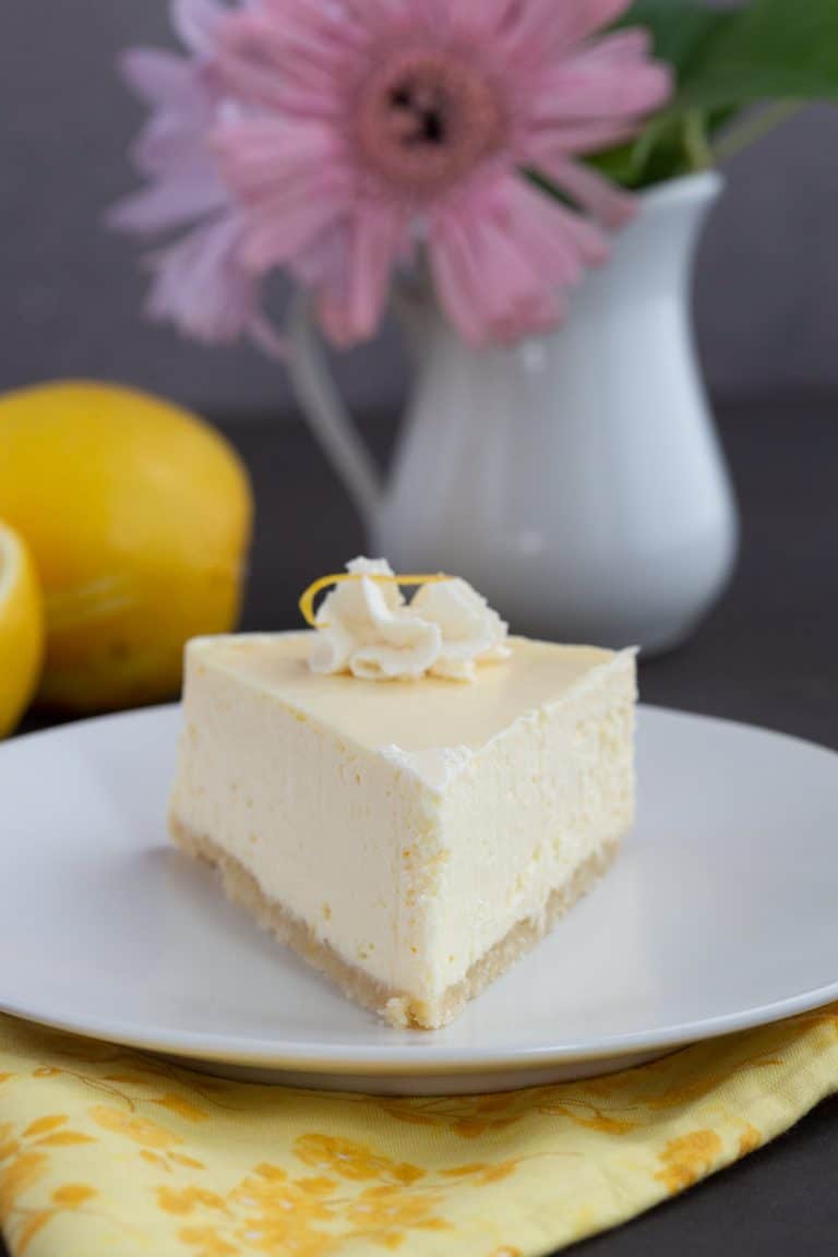 A slice of Keto Instant Pot Cheesecake on a white plate over a yellow flowery napkin.