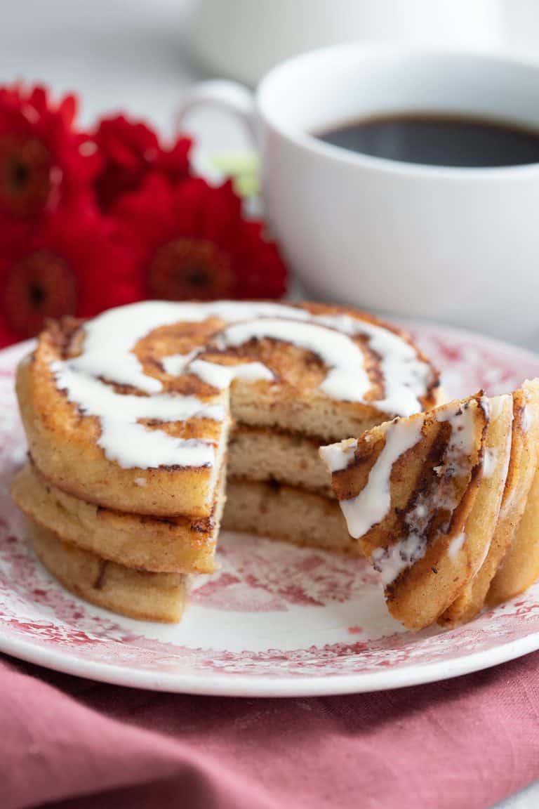 A stack of cinnamon roll pancakes with a forkful taken out of it.