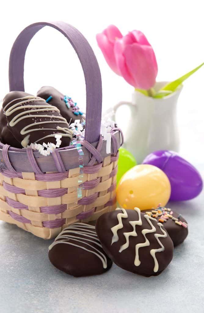 Keto chocolate easter eggs in front of an Easter basket and a vase with tulips.
