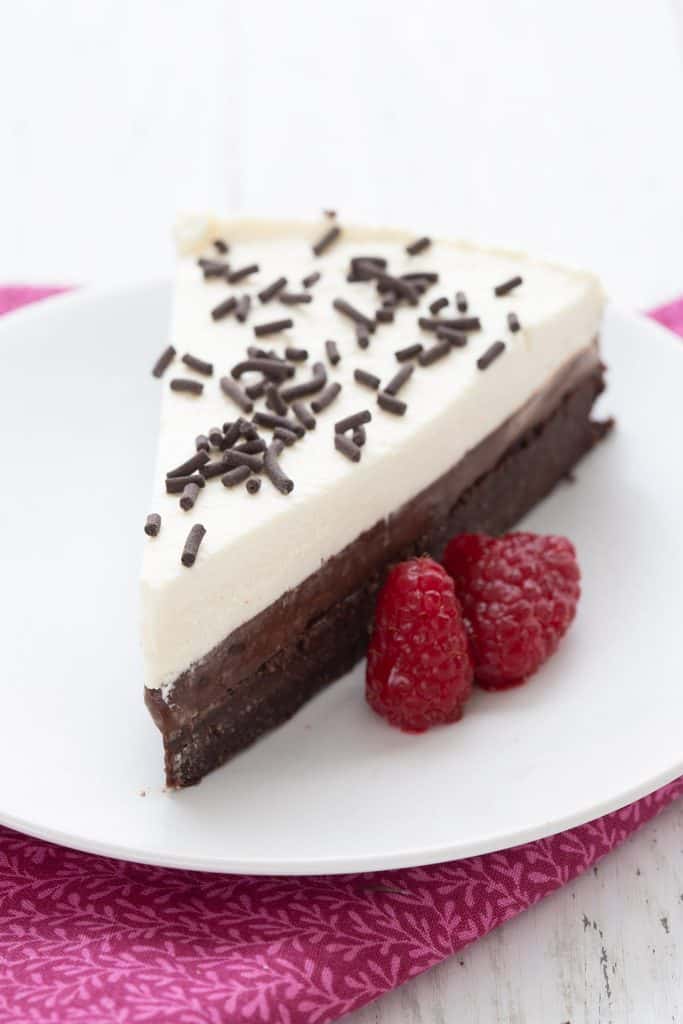 A slice of keto chocolate pudding pie on a white plate with raspberries.