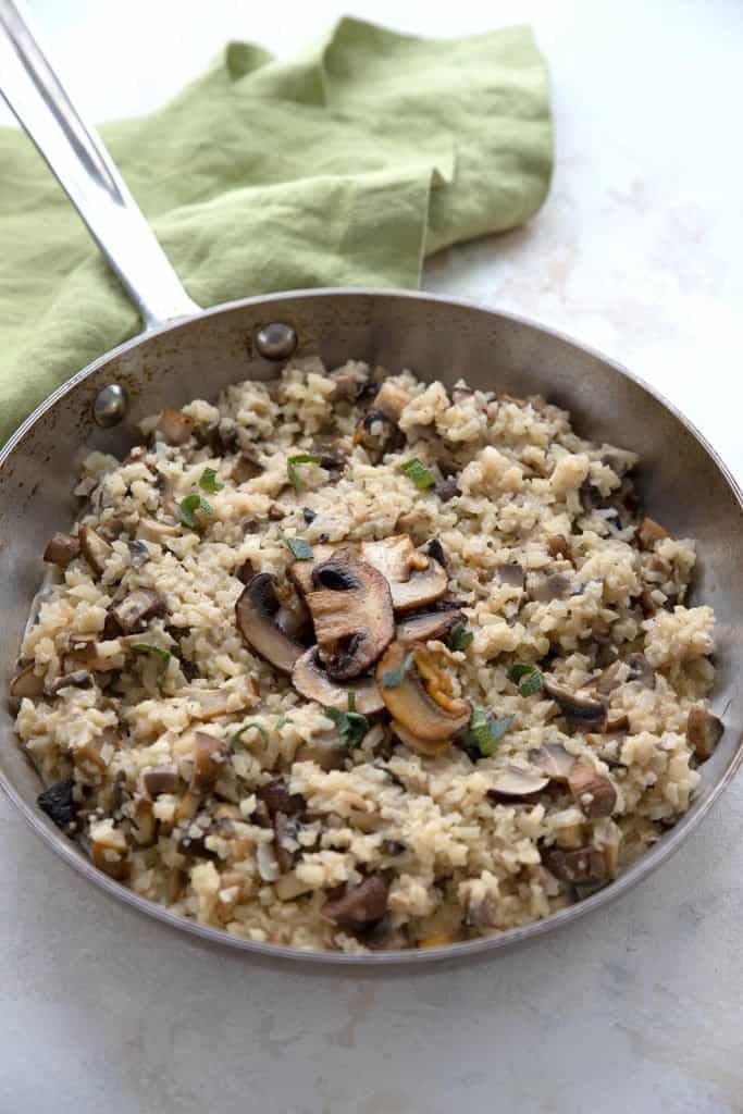 A metal pan filled with keto cauliflower risotto, with mushrooms on top.