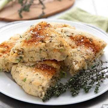 Savory almond flour scones on a white plate with some fresh thyme sprigs.