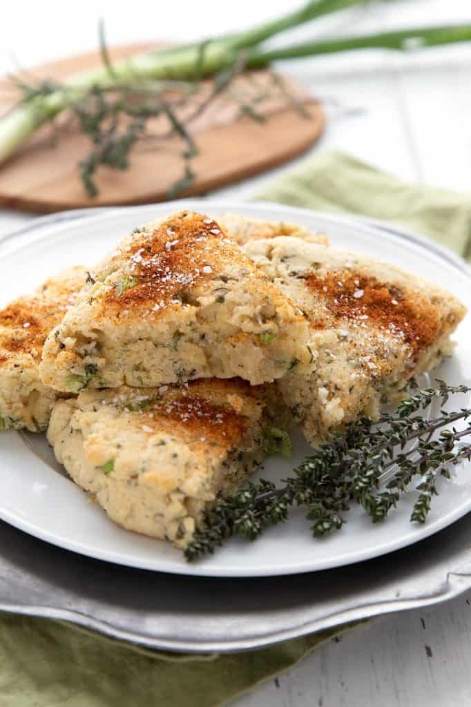 Savory almond flour scones on a white plate with some fresh thyme sprigs.