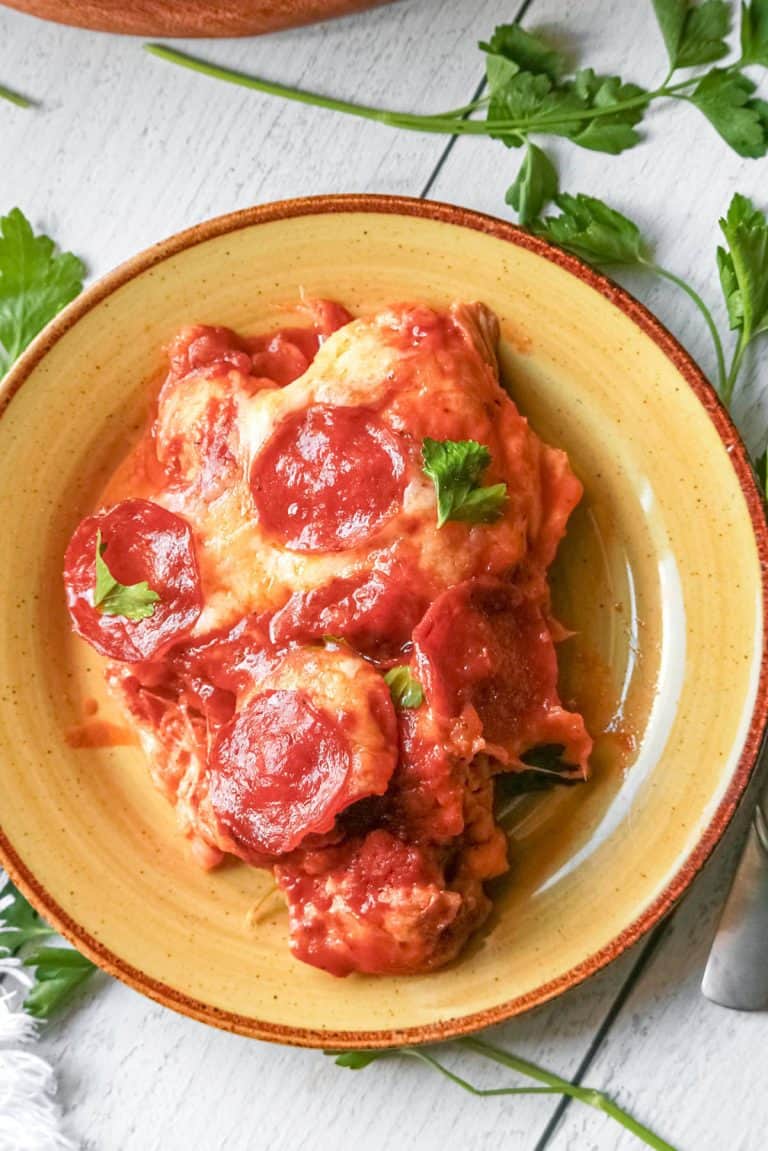 A serving of pizza chicken on a rustic yellow plate.