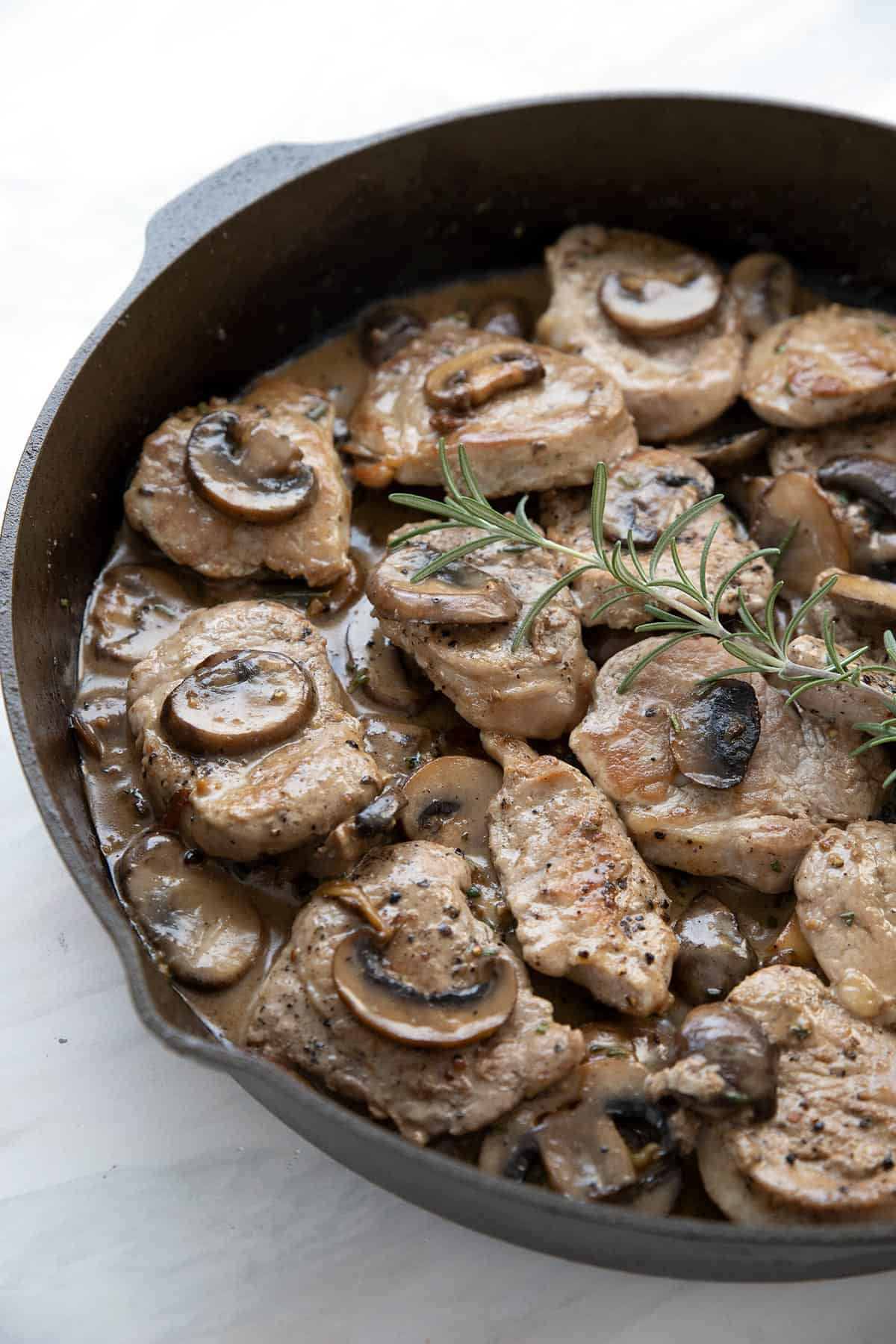 Pan seared pork medallions with creamy mushroom sauce in a cast iron skillet.