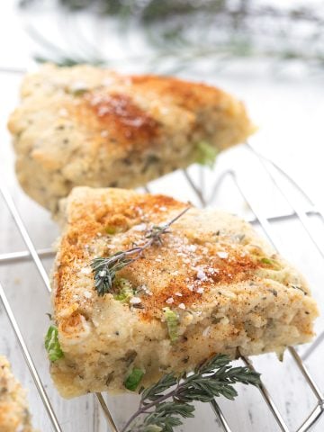 Savory keto herb scones on a cooling rack with fresh time around it.