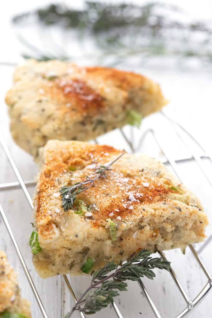 Savory keto herb scones on a cooling rack with fresh time around it.