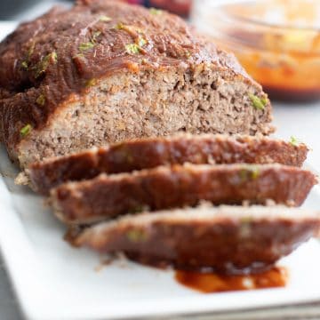 A white platter with keto meatloaf, with a few slices cut into the front.