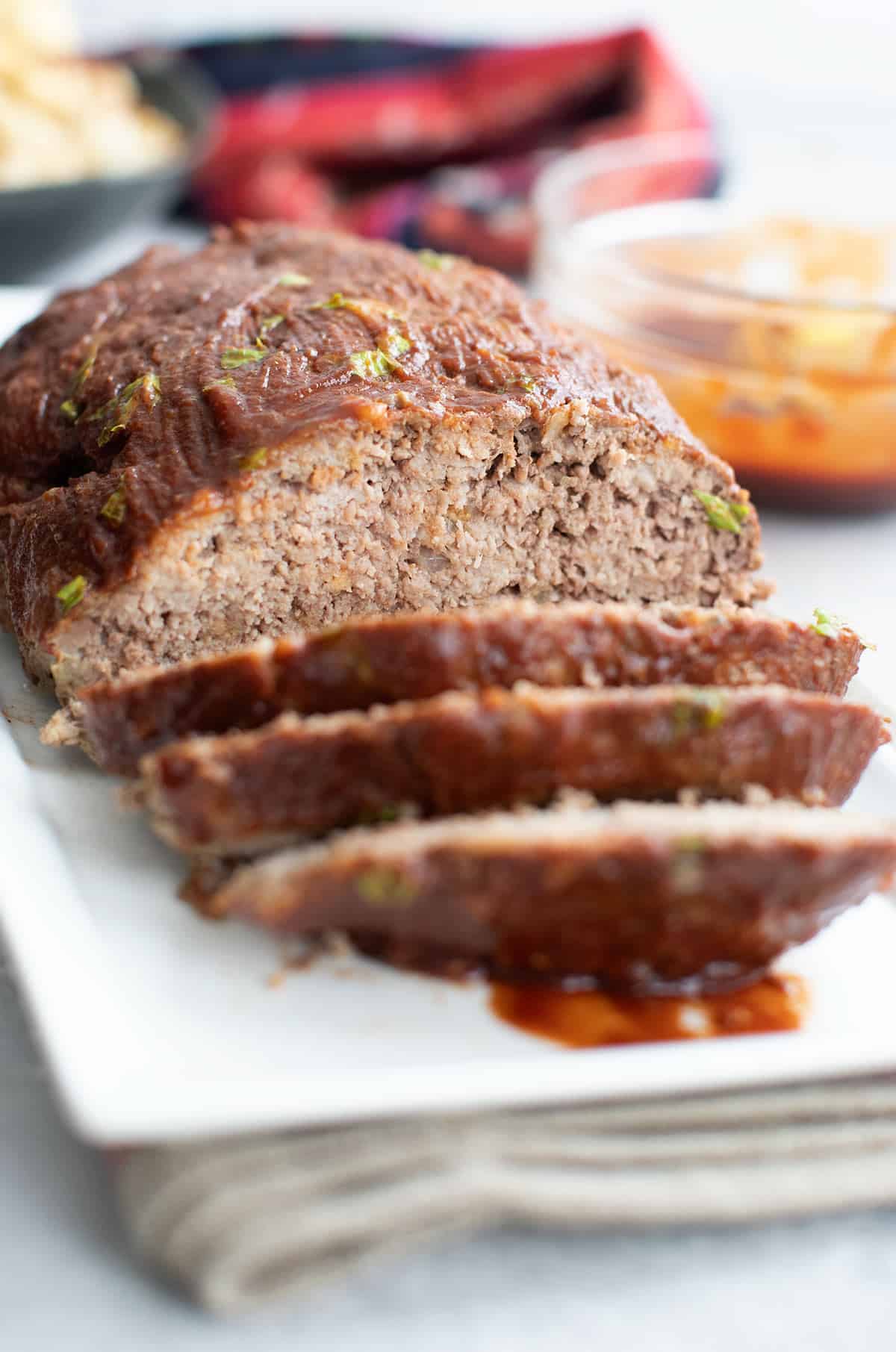 A white platter with keto meatloaf, with a few slices cut into the front.