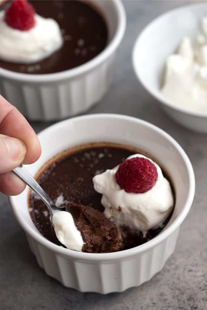 A hand digging a spoon into keto chocolate pots de creme.