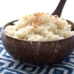 A coconut shell bowl filled with cauliflower rice over a blue patterned napkin.