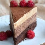 Close up shot of a slice of keto chocolate espresso mousse cake with fresh raspberries.