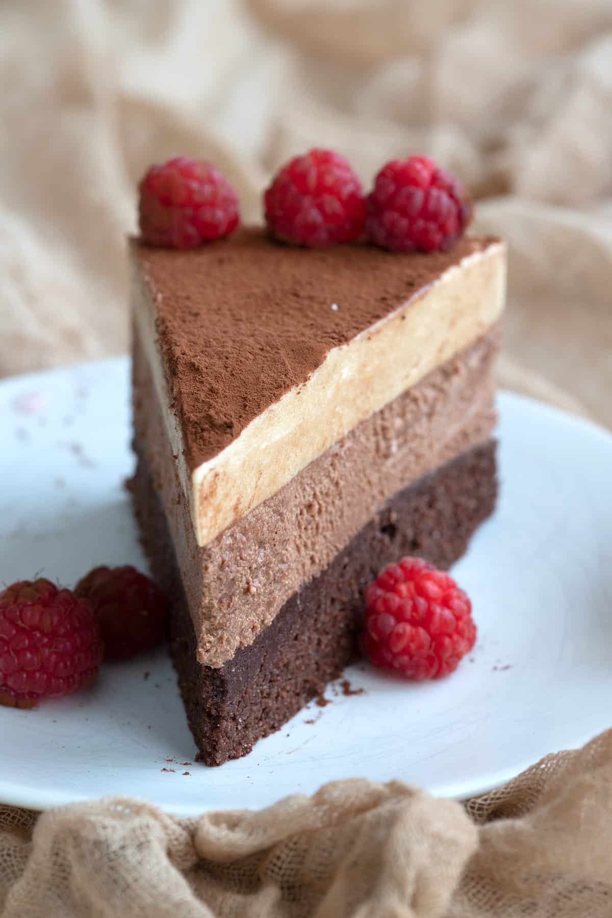 Close up shot of a slice of keto chocolate espresso mousse cake with fresh raspberries.