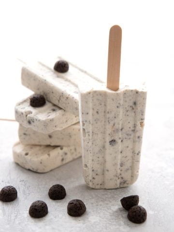 Cookies and Cream Popsicles in a pile on a grey table.