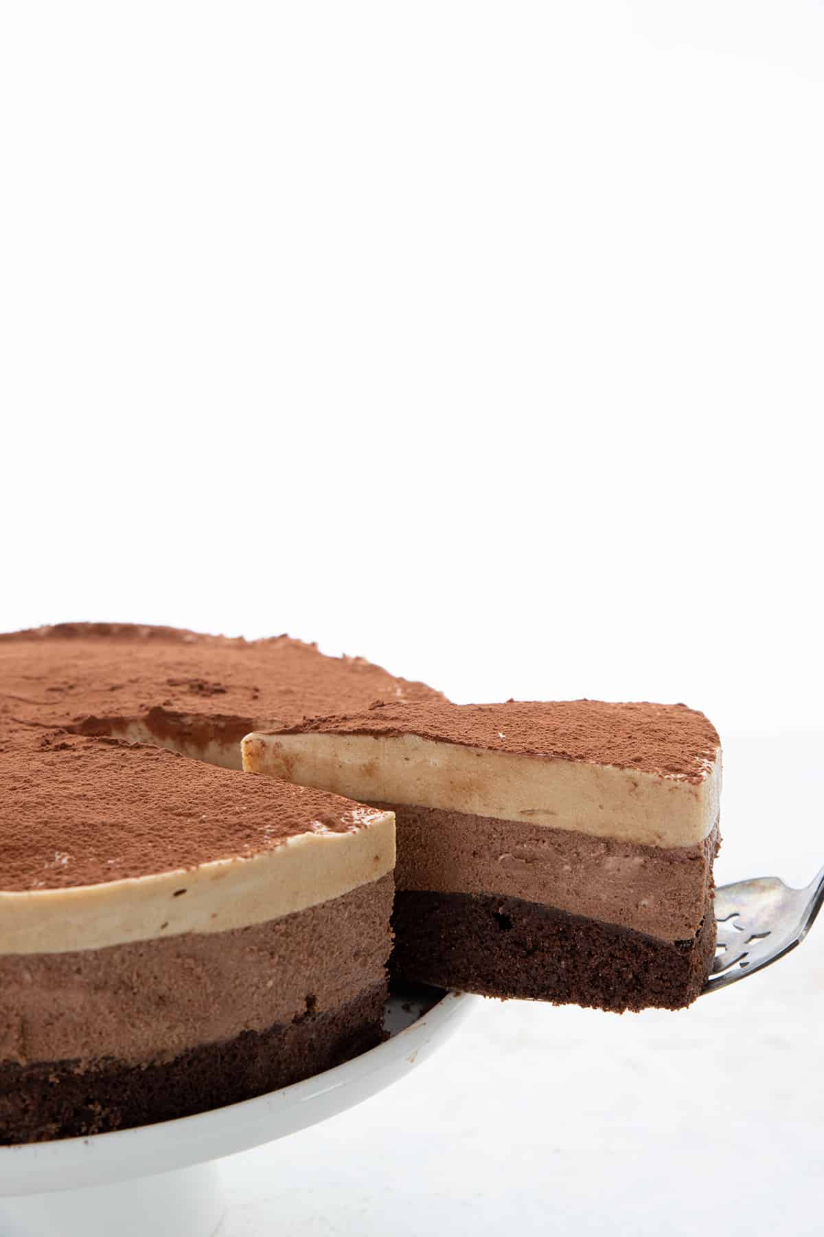 A slice of keto chocolate espresso mousse cake being lifted away from the main cake.