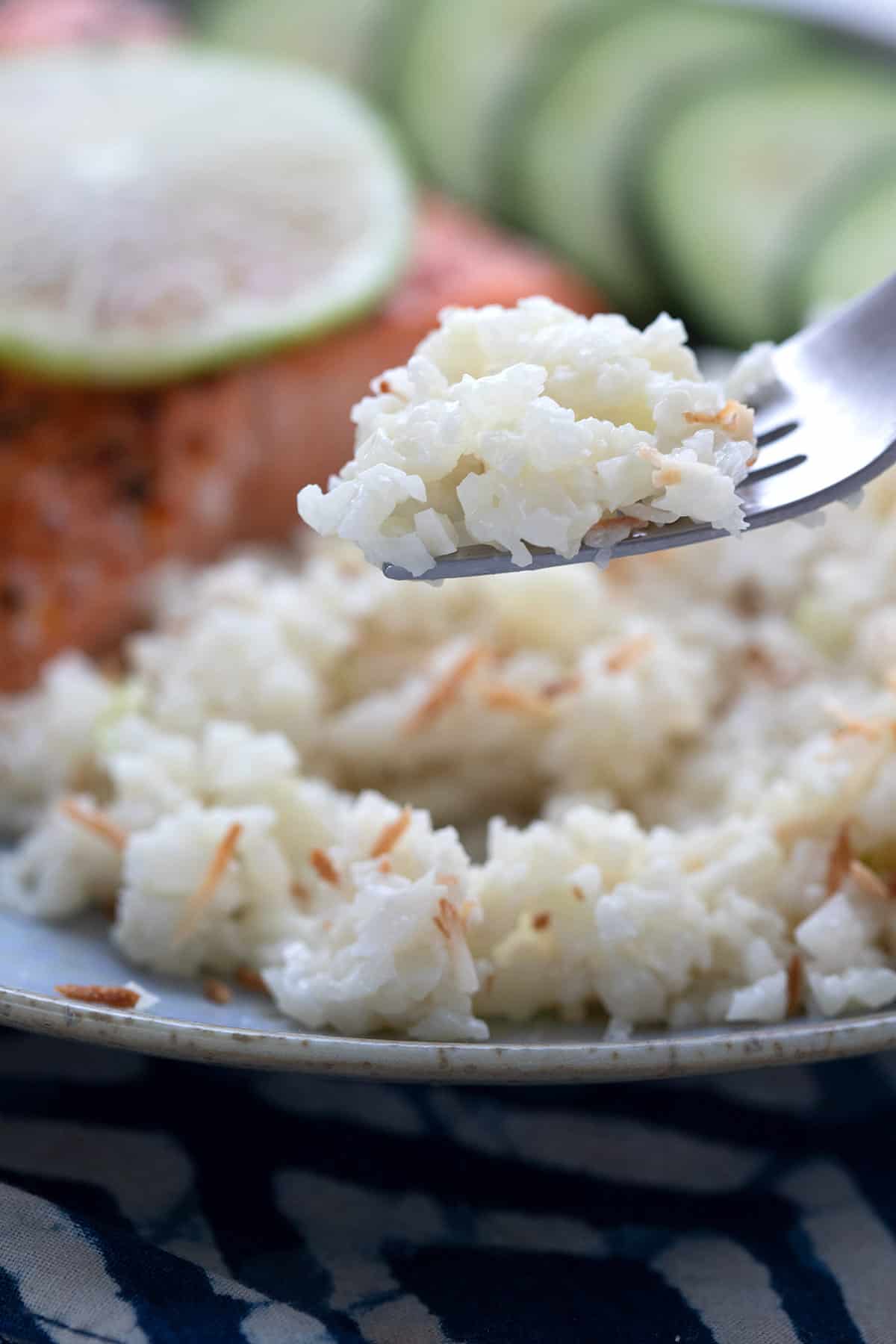 Close up shot of a fork lifting keto coconut cauliflower rice off a plate.