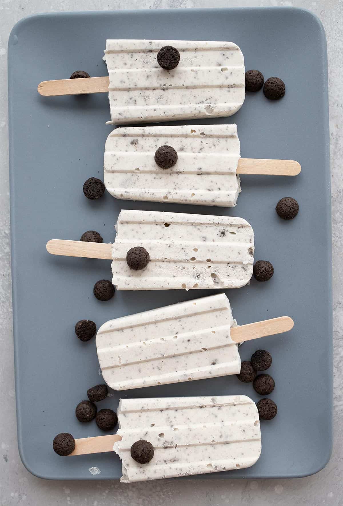 Top down image of keto cookies and cream popsicles on a blue plate.