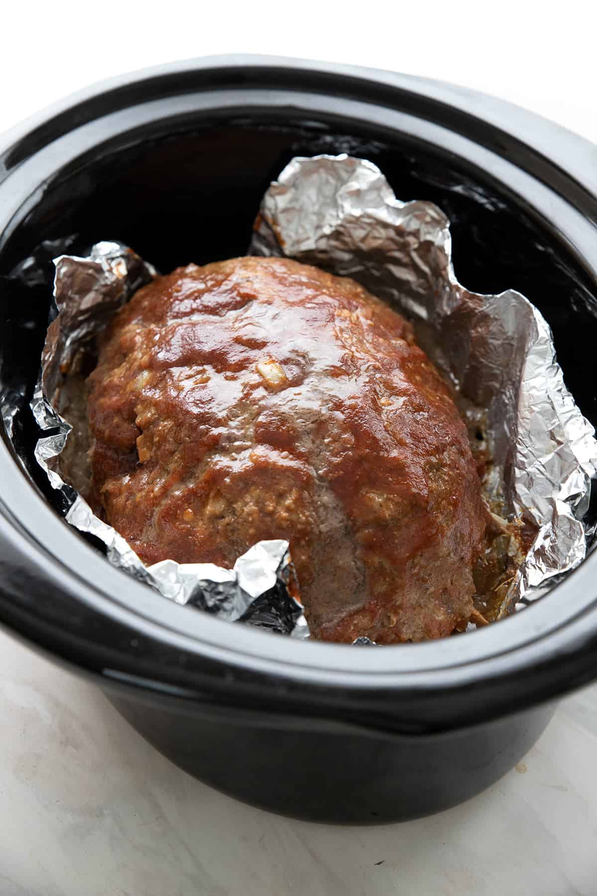 Keto meatloaf with bbq sauce in a crockpot lined with foil.