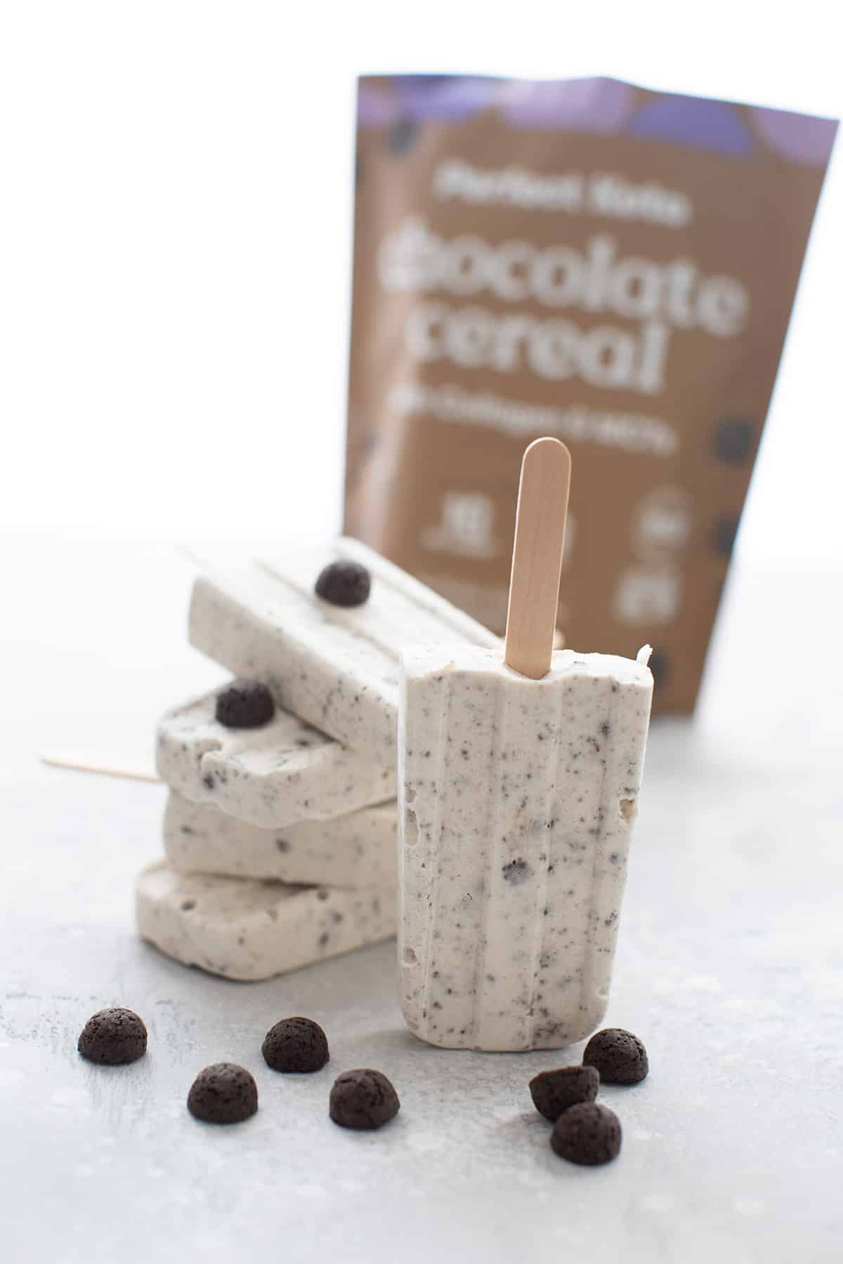 Keto Cookies and Cream Popsicles with a bag of chocolate keto cereal in the background.
