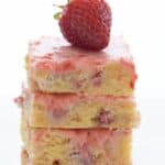 Titled image of a stack of Keto Strawberry Lemon Blondies with a fresh strawberry on top.