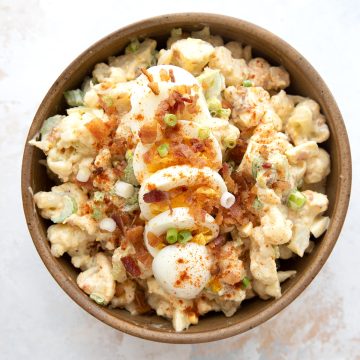 Top down image of cauliflower salad in a serving bowl, with sliced hard boiled eggs on top.