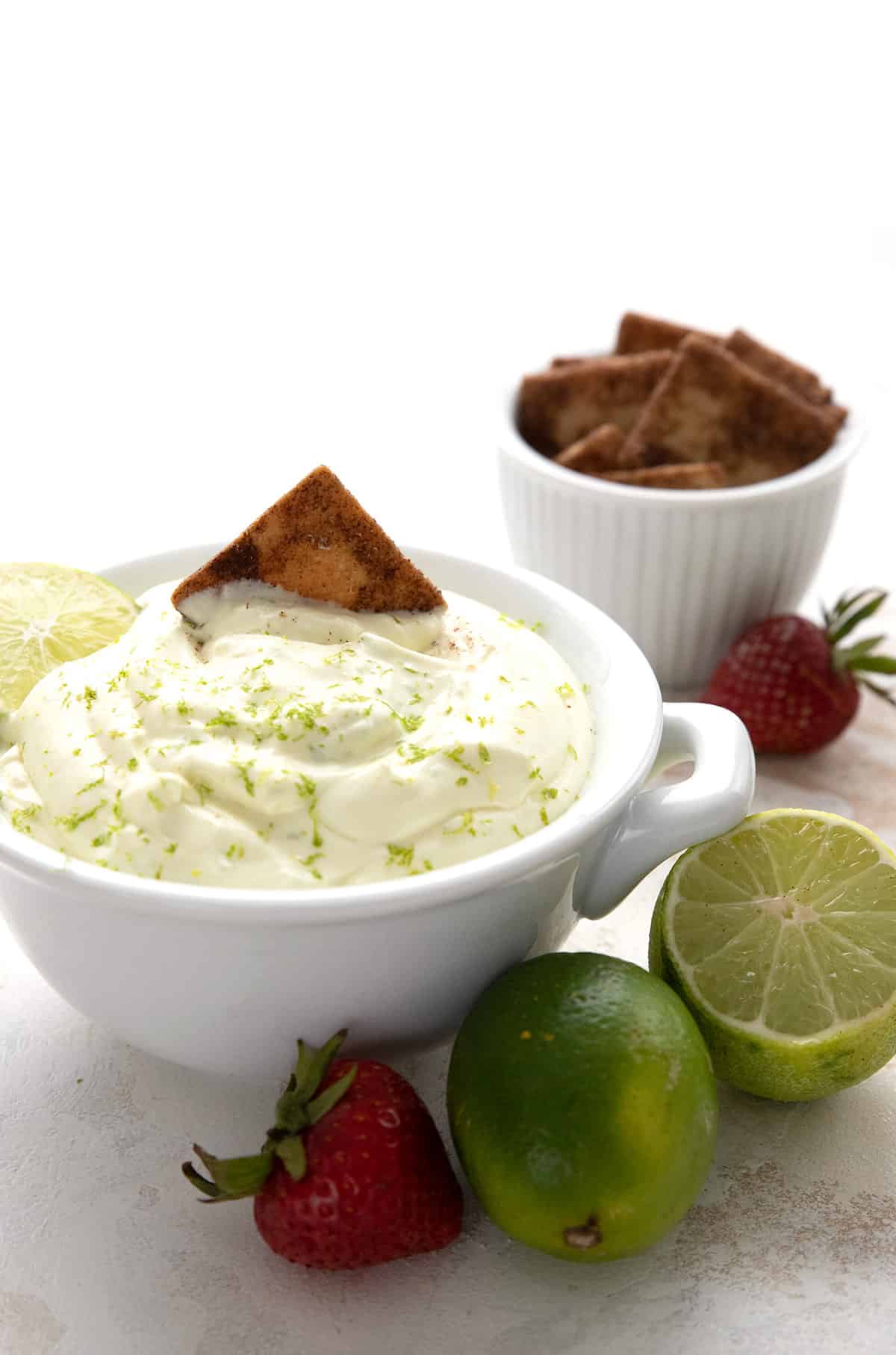 Keto cinnamon crackers being dipped into a bowl of key lime pie dip.