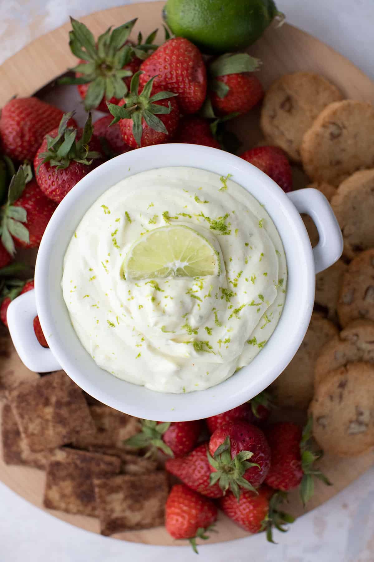 Top down image of keto key lime dip surrounded by keto cookies, crackers, and strawberries.