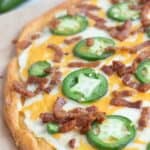 Keto Jalapeno Popper Pizza on a cutting board with fresh jalapeños in the background.