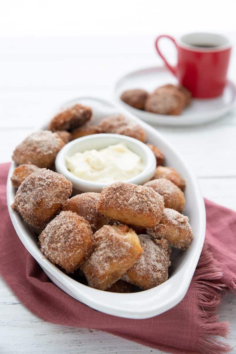 Cinnamon pretzel bites in a white oval dish, over a dark red napkin.