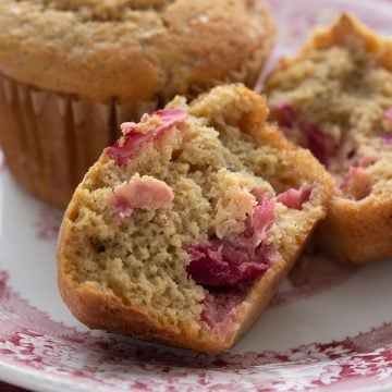 Close up shot of a keto rhubarb muffin, broken open, on a red patterned plate.