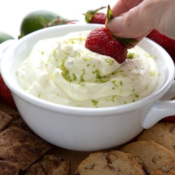 Dipping a strawberry into a bowl of keto fruit dip.