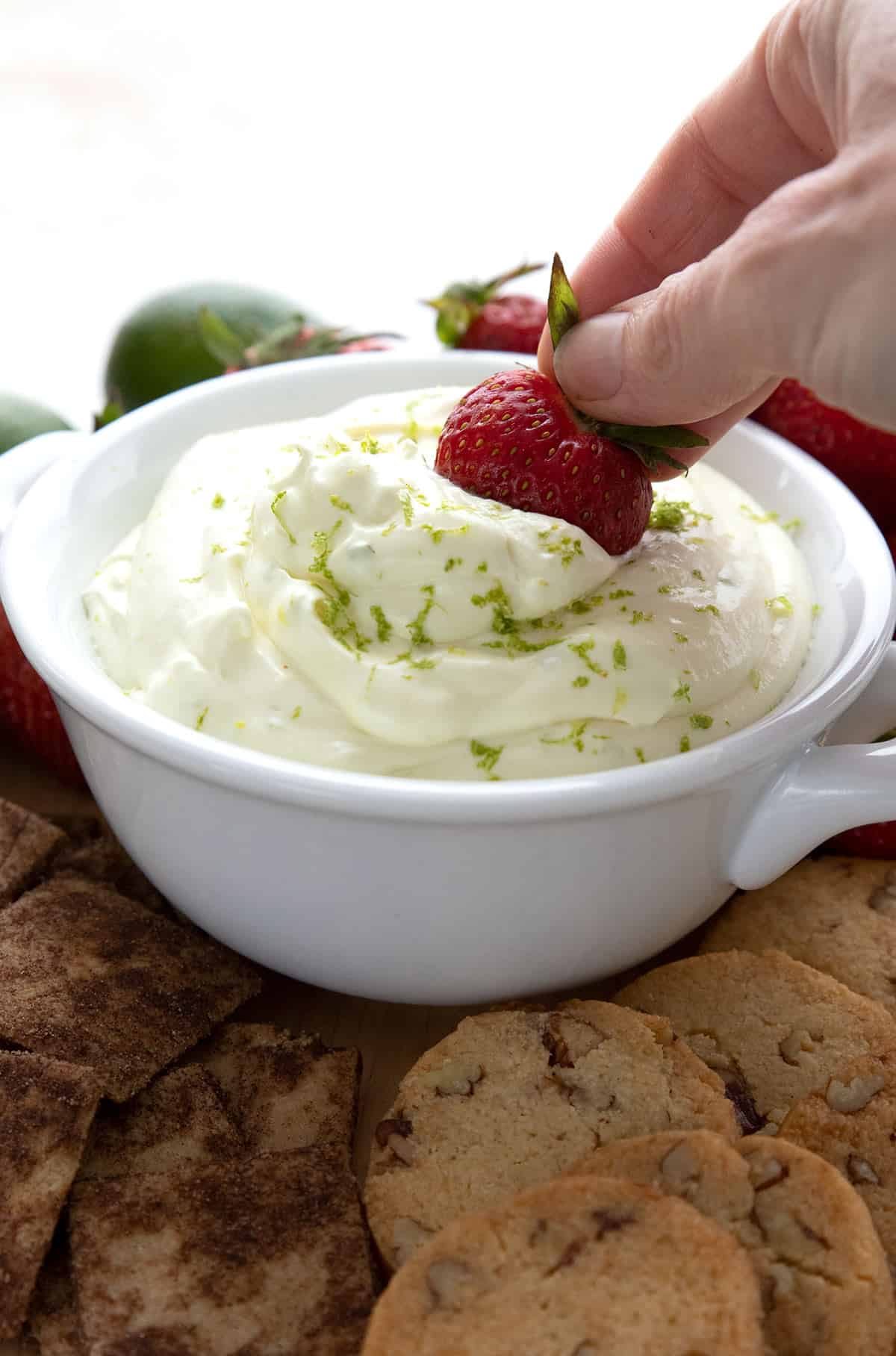 Dipping a strawberry into a bowl of keto fruit dip.