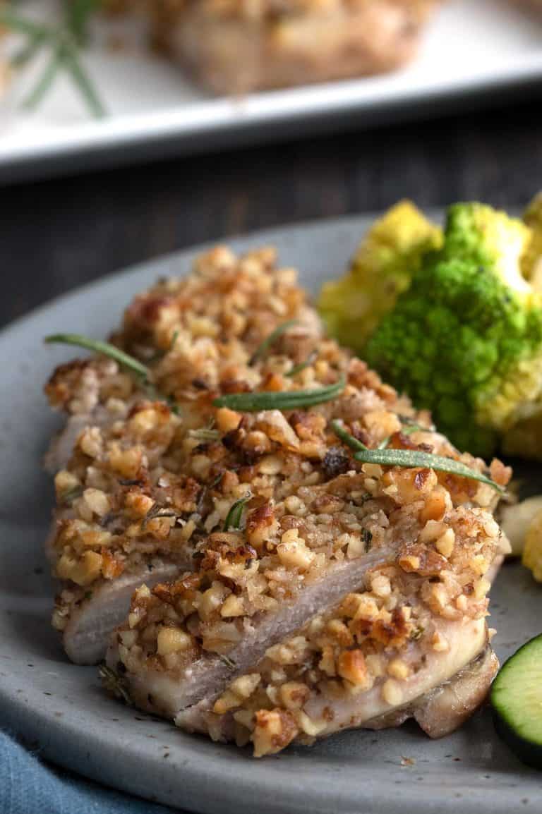 A piece of walnut chicken in slices on a grey plate.