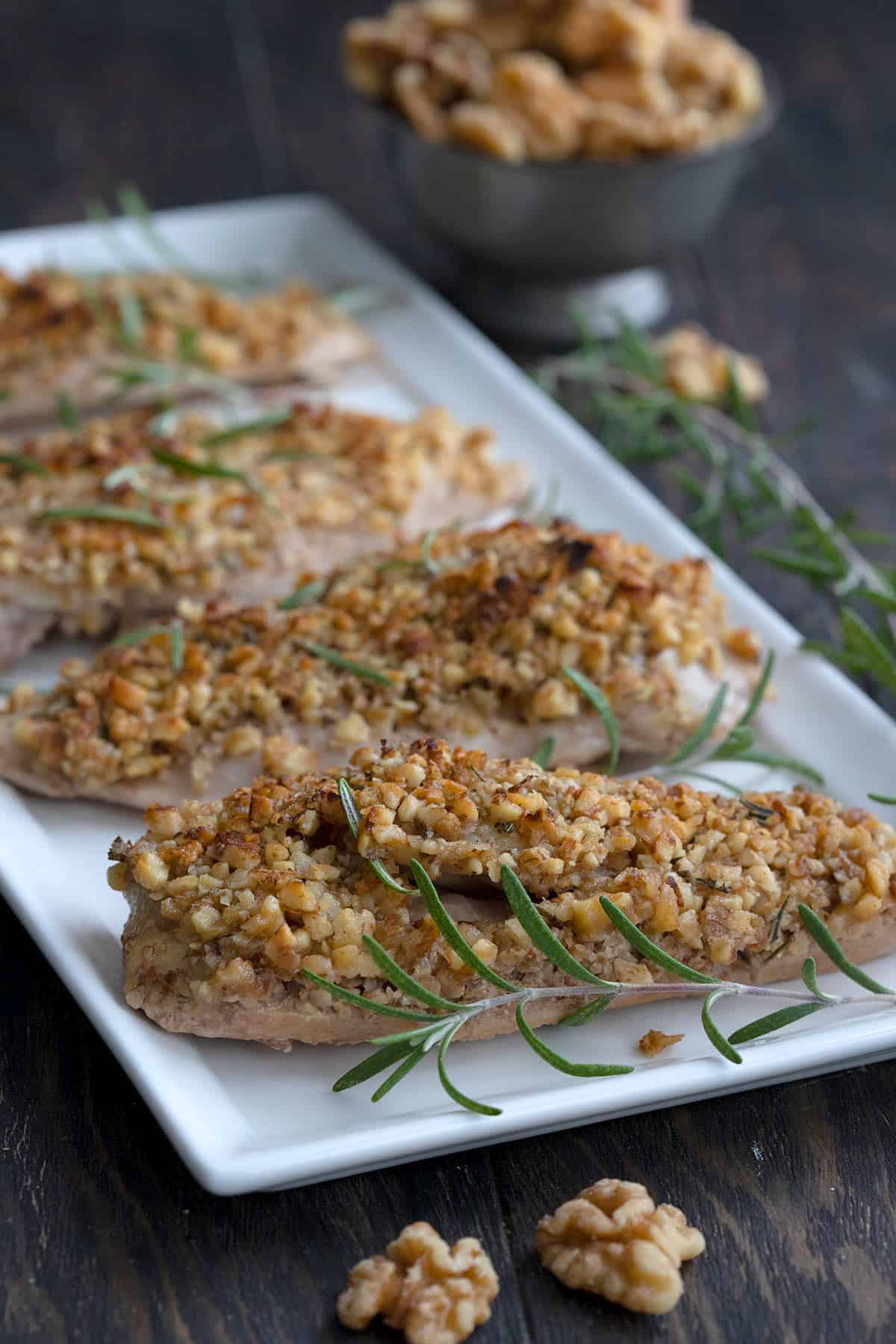 A white platter filled with walnut crusted chicken.