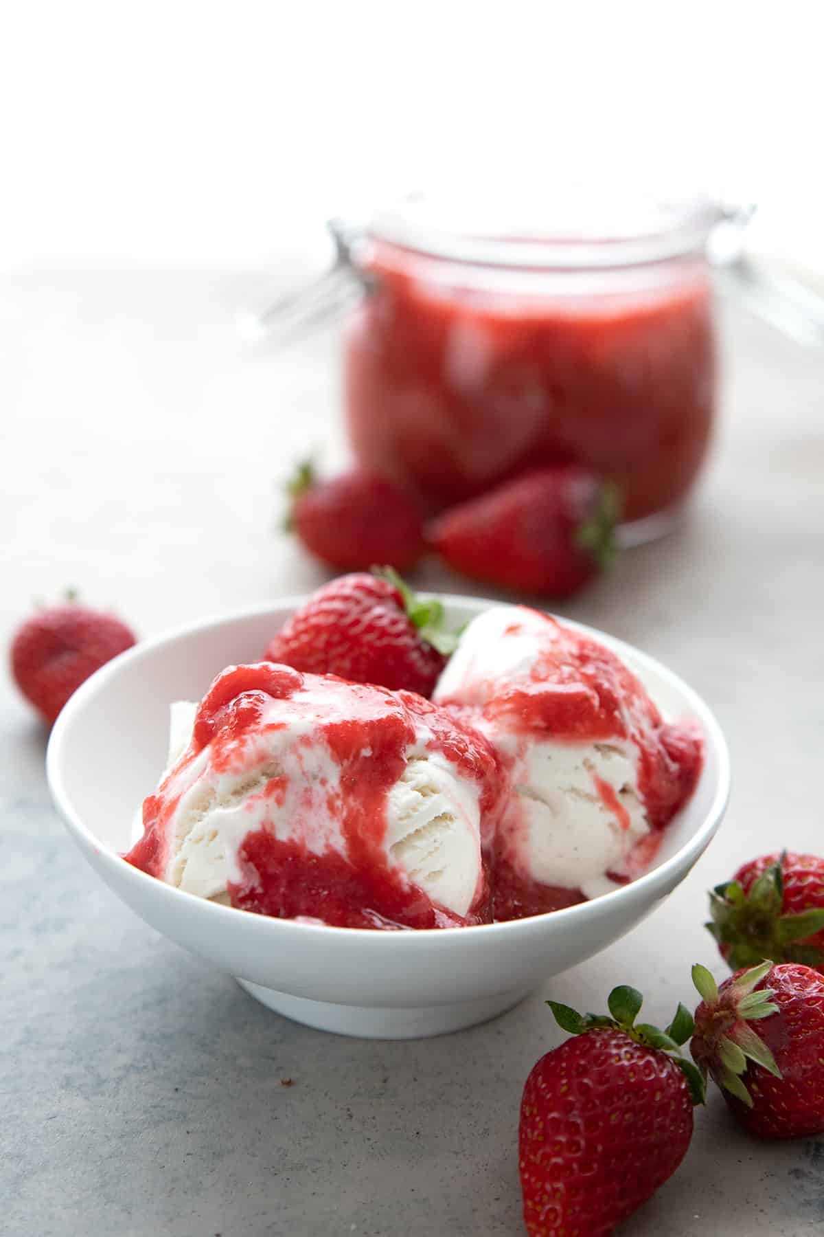 A bowl of keto vanilla ice cream topped with strawberry rhubarb sauce.
