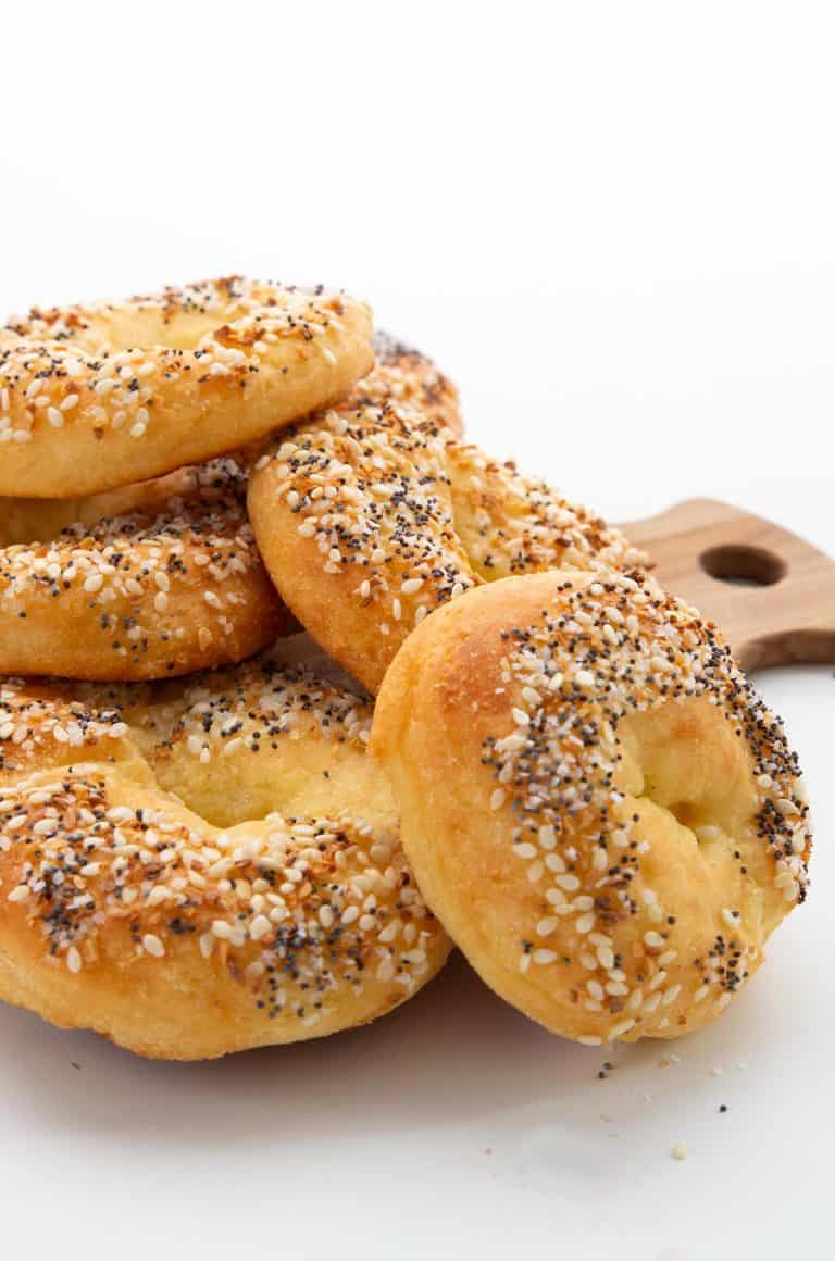 A pile of keto bagels on a wooden cutting board.