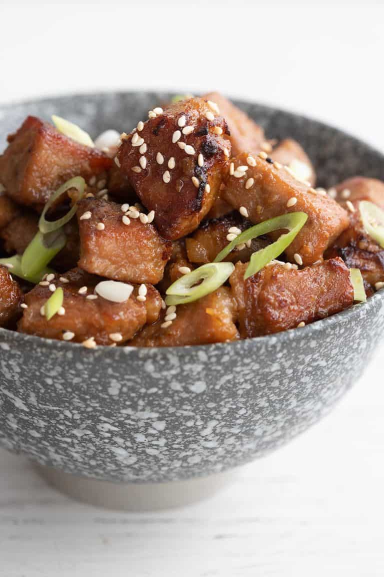 Close up shot of honey garlic pork bites in a gray bowl.