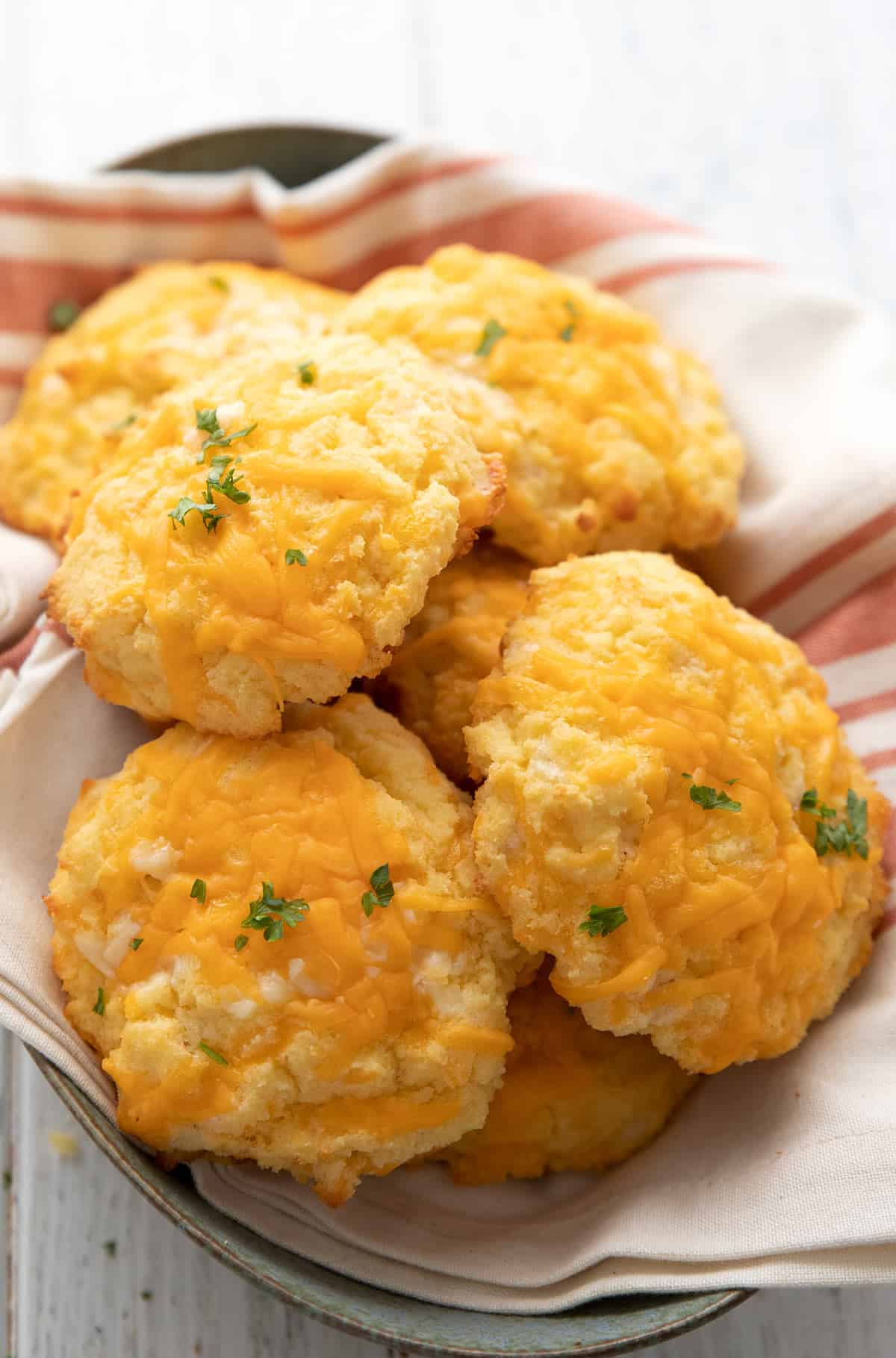 Easy keto biscuits piled in a bread basket over an orange striped napkin.