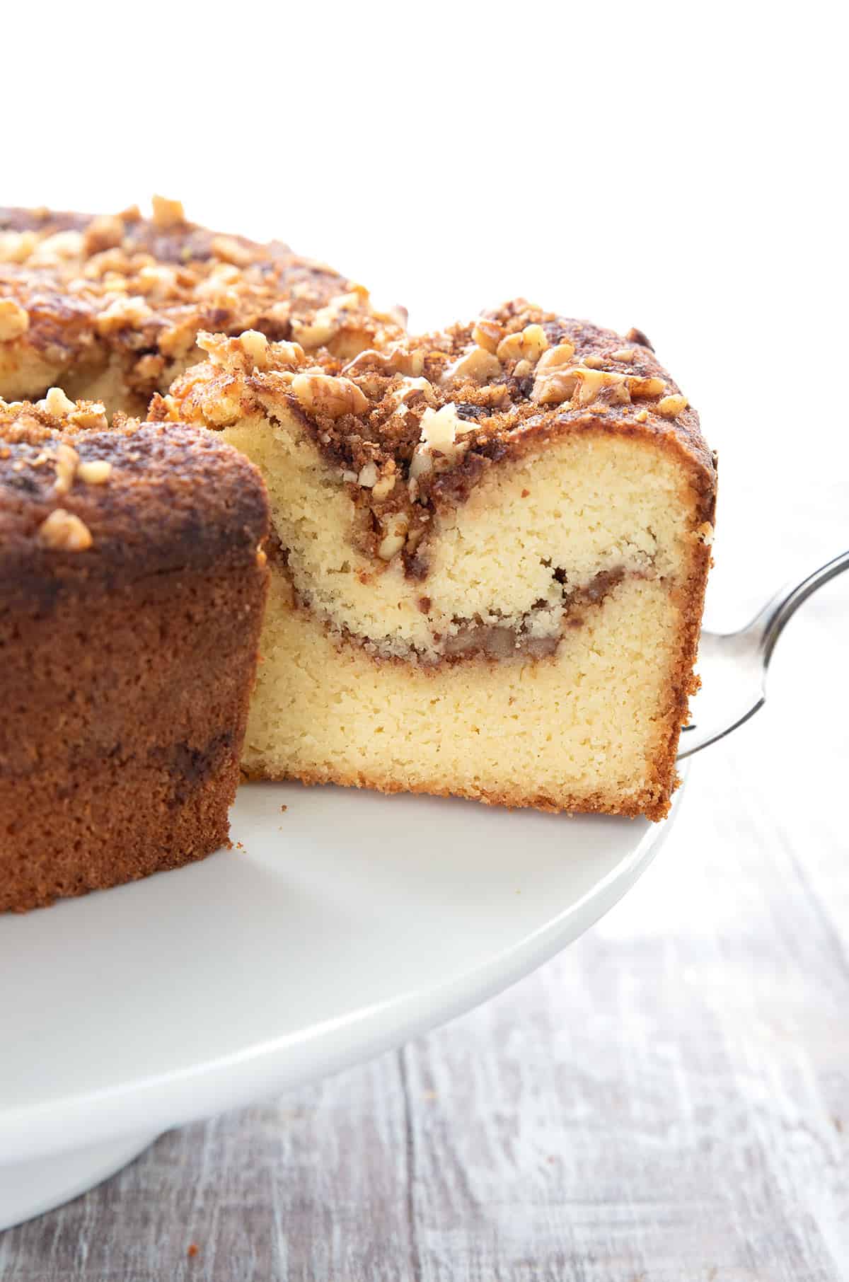 A slice of keto coffee cake being pulled away from the rest of the cake on a cake server.