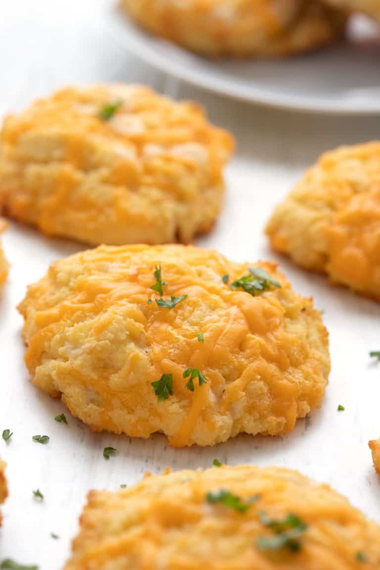 Keto biscuits in a line on a white wooden table.