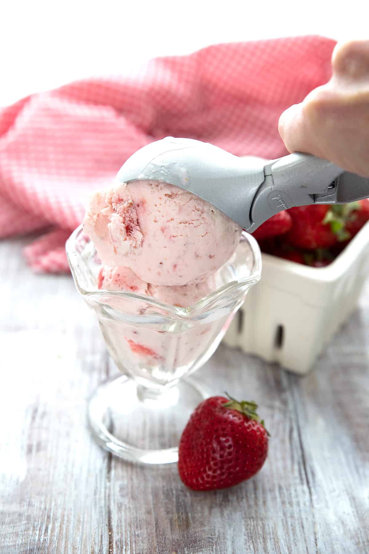 An ice cream scoop placing a scoop of keto ice cream into a glass dish.