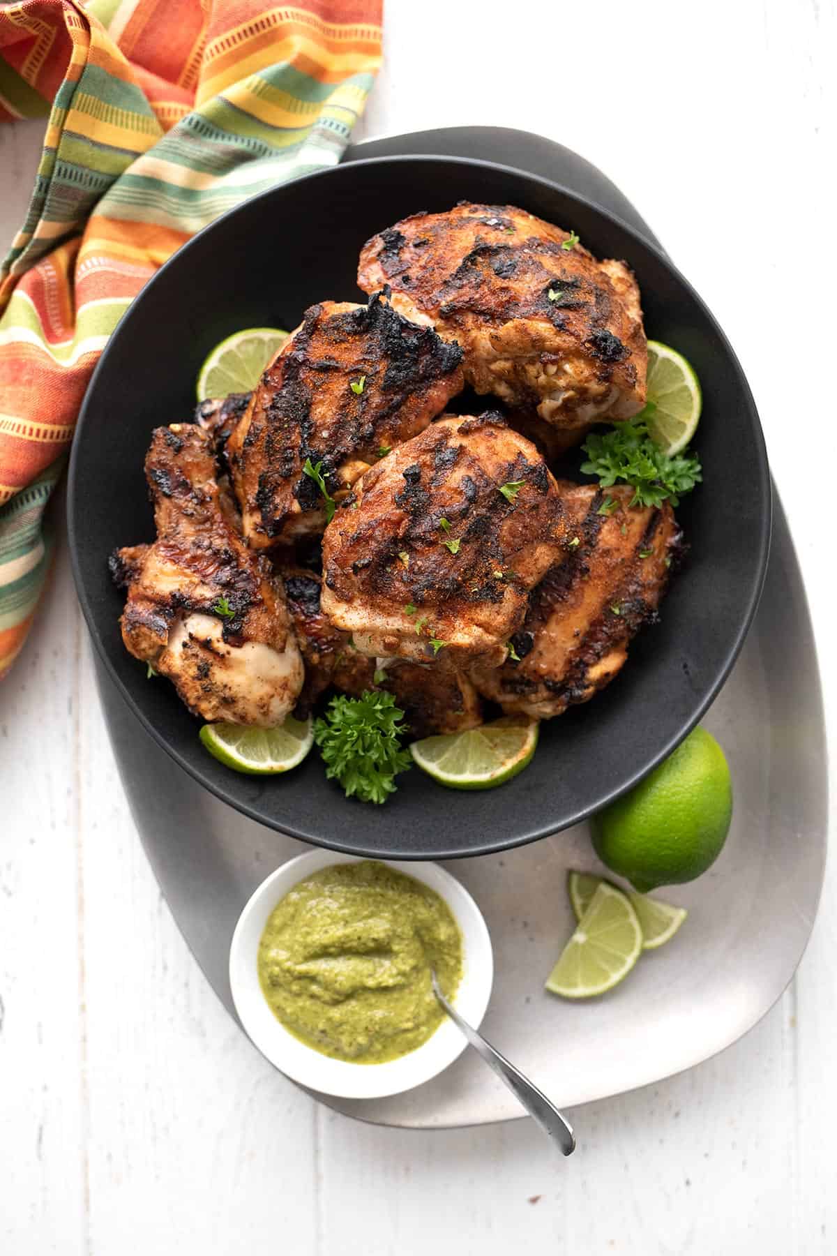 Top down image of a metal tray with Peruvian chicken and cilantro sauce.