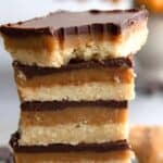 Titled image of a stack of keto Tagalong bars on a gray table with chocolate chips strewn around.