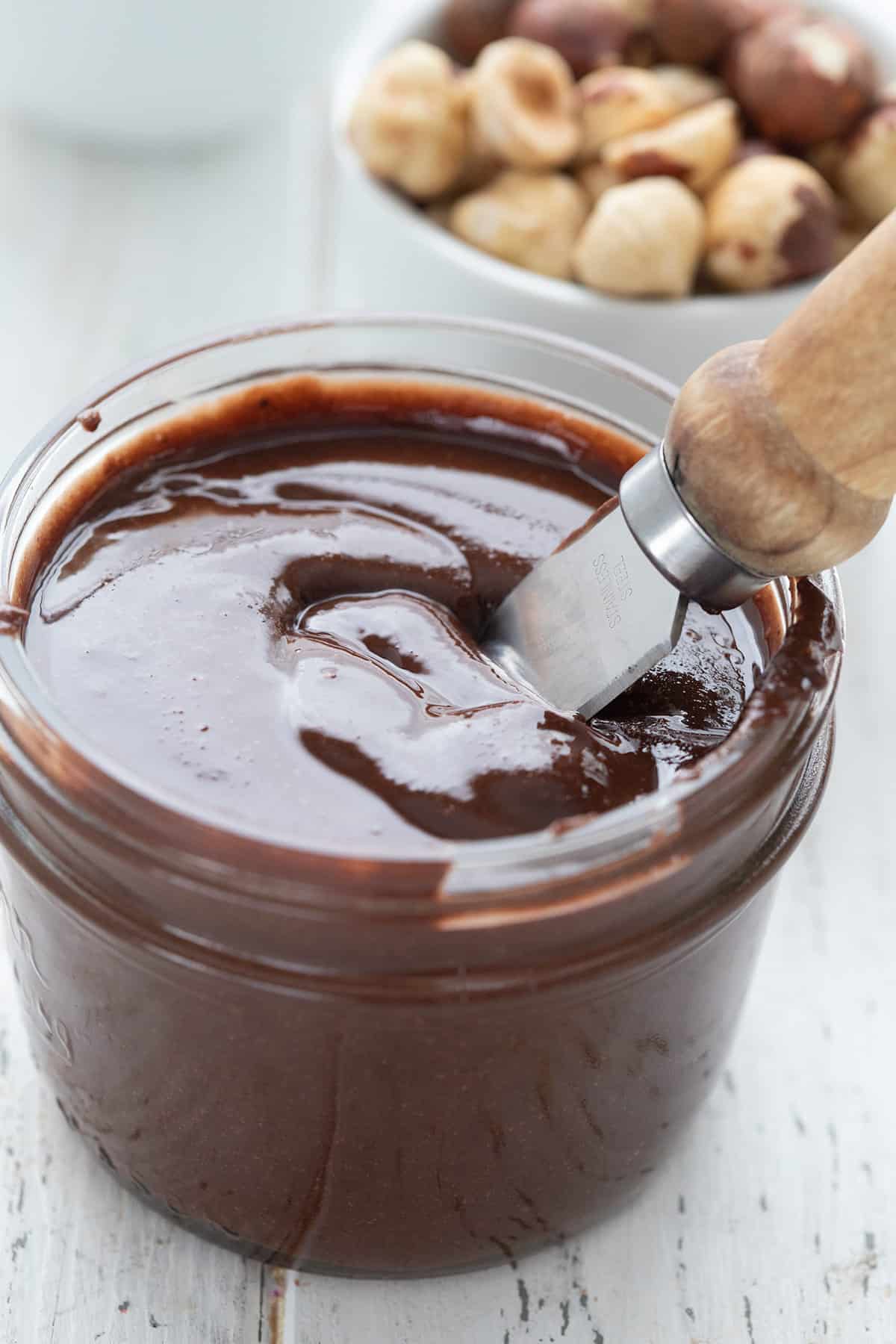 Nærbilde av en kniv som graver ned i en krukke med sukkerfri Nutella.