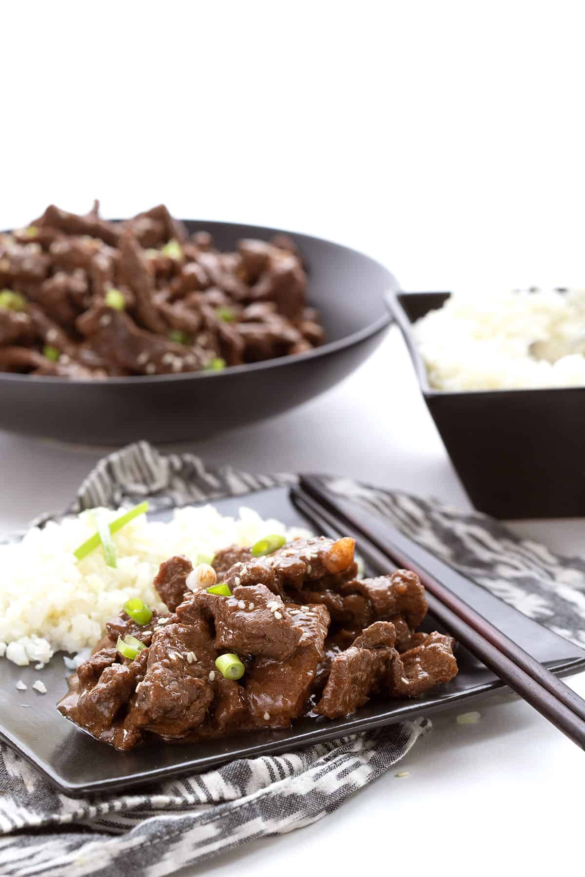 A plate of Keto Mongolian Beef with cauliflower rice and chopsticks.